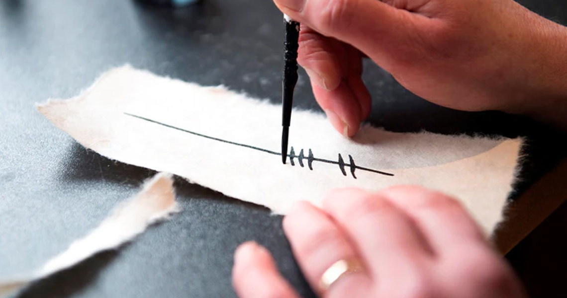 Woman hand painting Ogham at the Bastion Gallery.