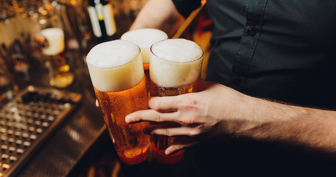 Bartender serving three pints at Lord Bellamy's Bar.