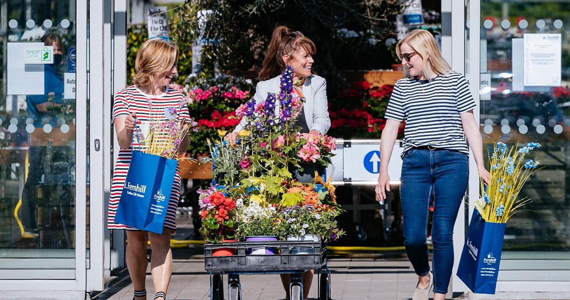 Woman walking out with their purchases from Fernhill Garden Centre.