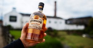 Man holding a bottle of Kilbeggan Irish Whiskey outside the distillery.