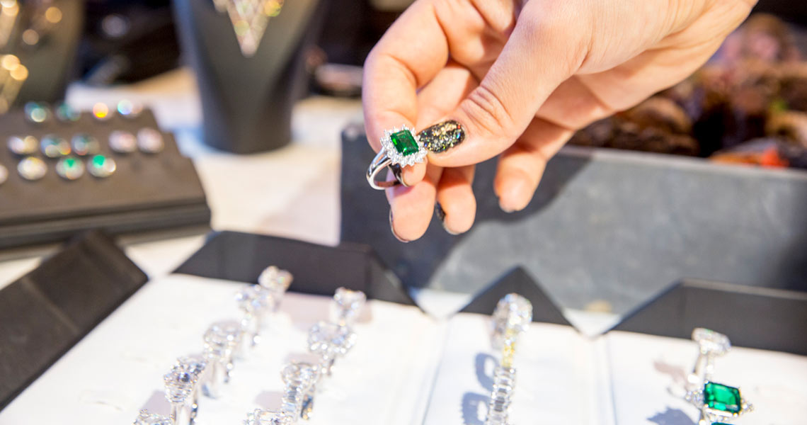 Jewellers holding an emerald ring.