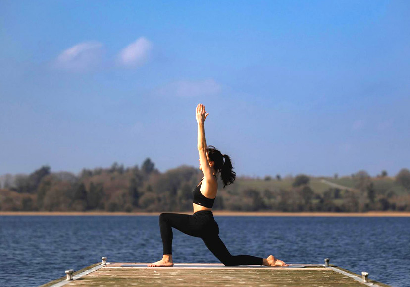Woman performing yoga on the pier at Cedarwood Spa.